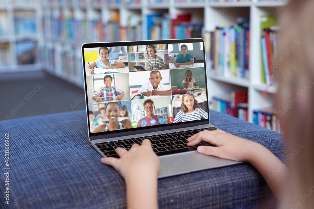 Caucasian girl using laptop for video call, with smiling diverse high school pupils on screen