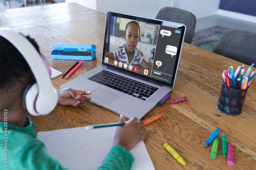 African american boy using laptop for video call, with elementary school pupil on screen