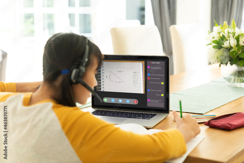 Asian girl using laptop for video call, with class on screen