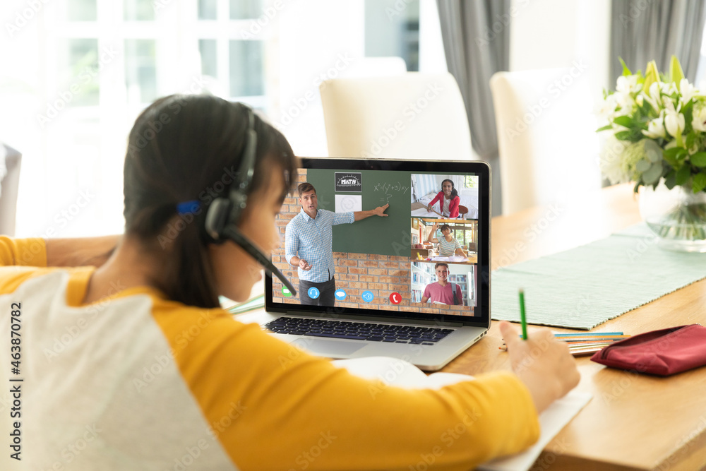 Asian girl using laptop for video call, with smiling diverse high school pupils on screen