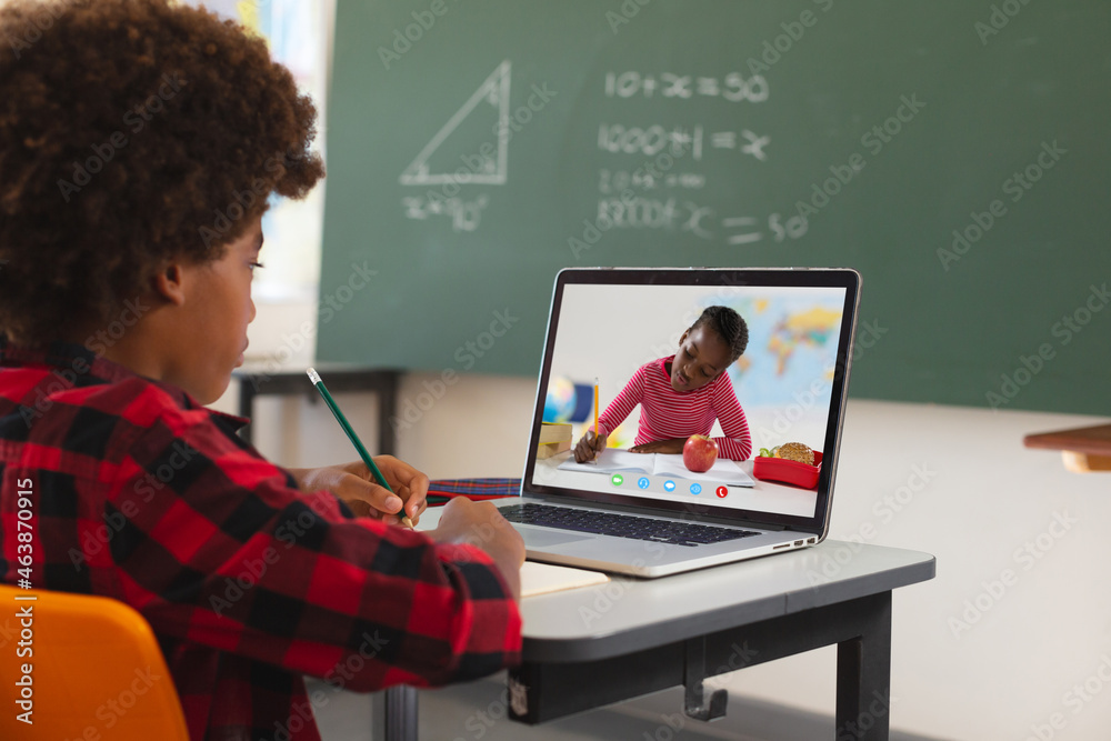 African american boy using laptop for video call, with elementary school pupil on screen