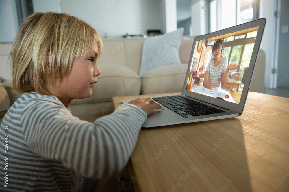 Smiling caucasian boy using laptop for video call, with elementary school pupil on screen