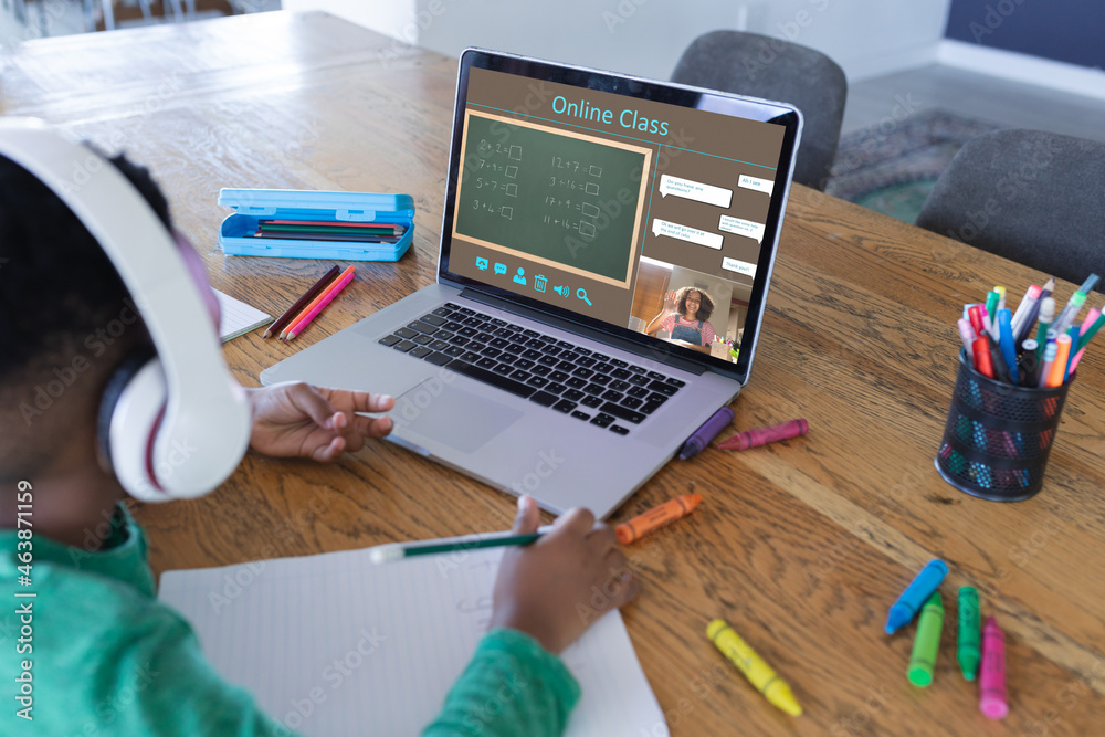 African american boy using laptop for video call, with class on screen