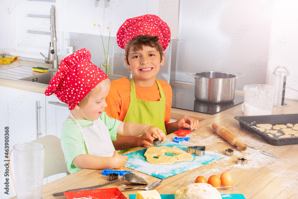 Children cut out forms from dough for cookies