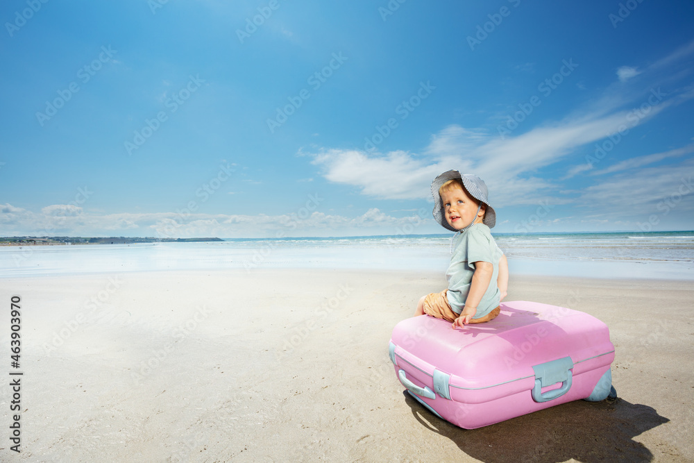 Vacation concept a boy sit on suite case at beach