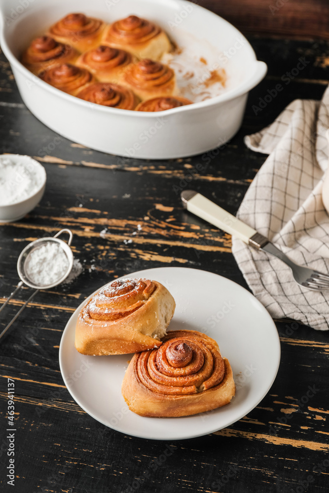 Plate with tasty cinnamon rolls on table