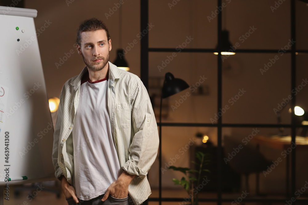 Young man giving presentation in office late in evening