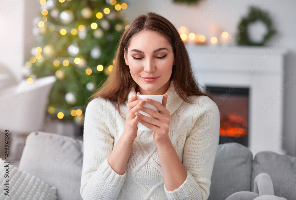 Beautiful young woman with cup of hot cacao drink at home on Christmas eve