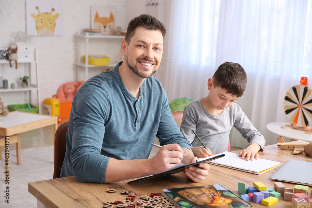 Male psychologist working with little boy in office. Autism concept