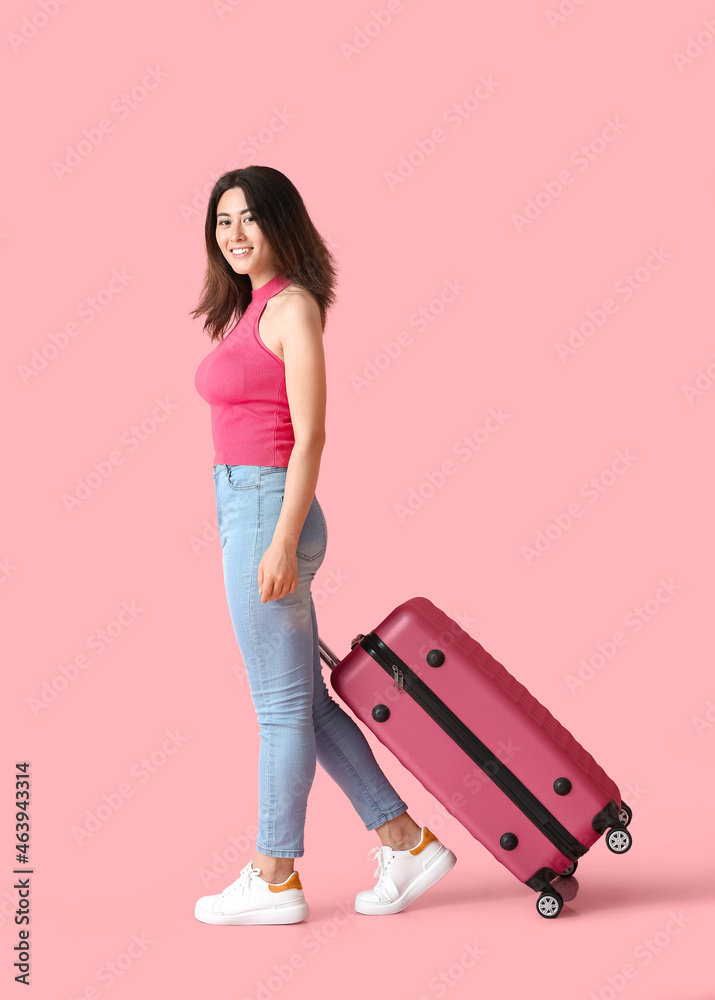 Young woman with suitcase on color background