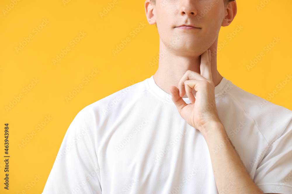 Sporty young man counting pulse on color background