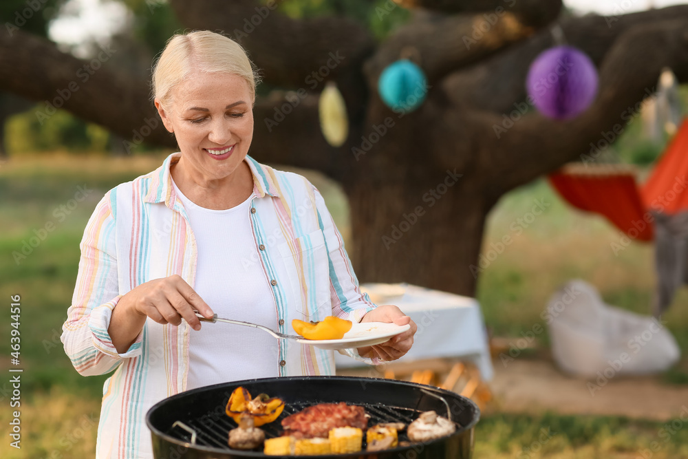 成熟女人在户外烧烤架上烹饪食物