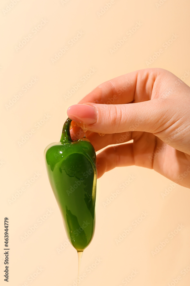 Woman holding jalapeno pepper with honey on color background, closeup