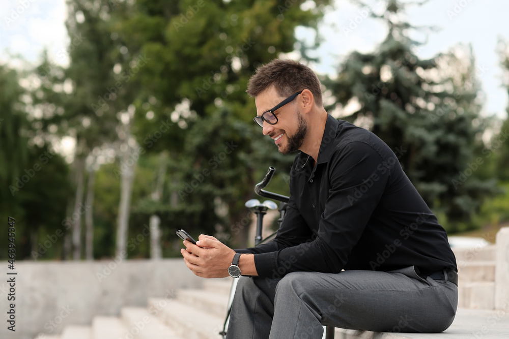 Businessman with bicycle and mobile phone on city street