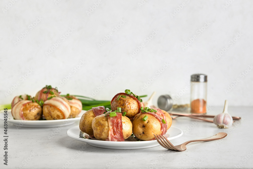 Plates of tasty baked potatoes with bacon on light background