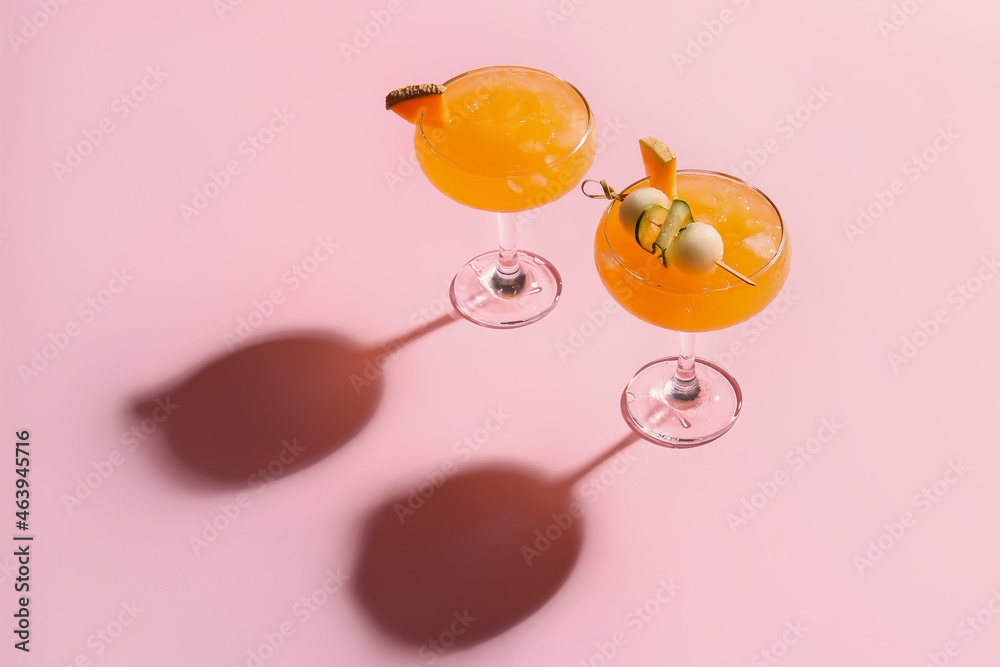 Glasses of melon cocktail on pink background