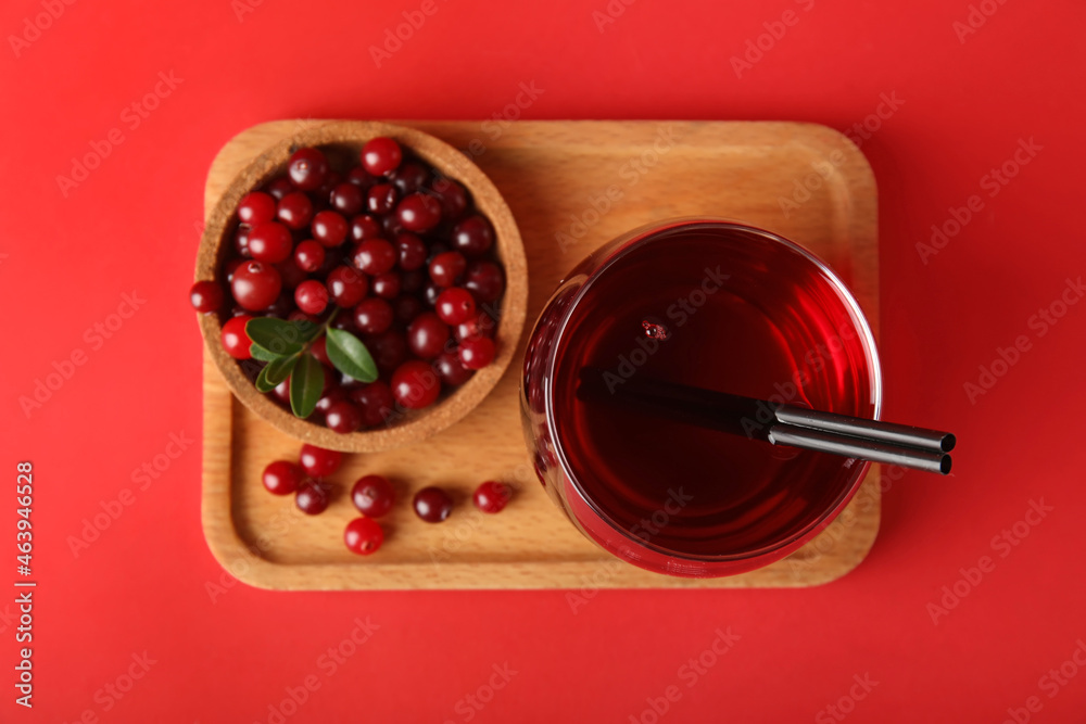 Glass of healthy juice and bowl with cranberries on color background