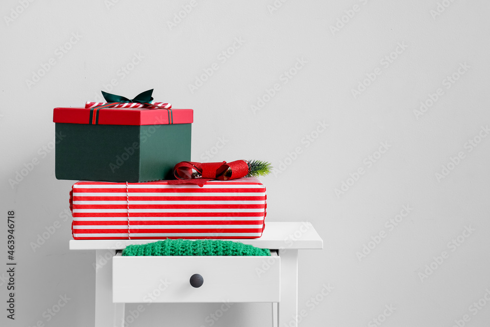 Beautiful Christmas gifts on table near light wall