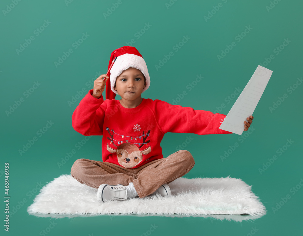 Cute African-American boy with letter to Santa on color background