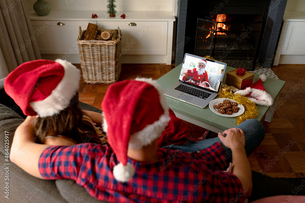 Caucasian couple in santa hats on laptop christmas video call with friends