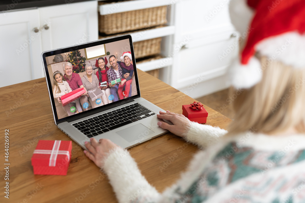 Caucasian woman on christmas laptop video call with diverse family