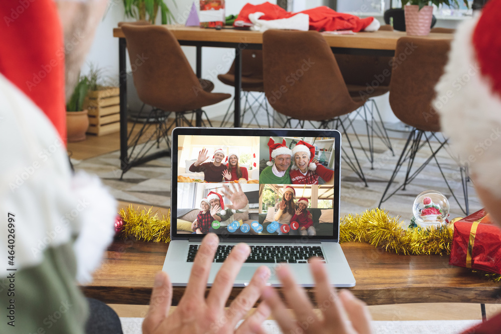 Caucasian couple on christmas laptop video call with diverse group of friends