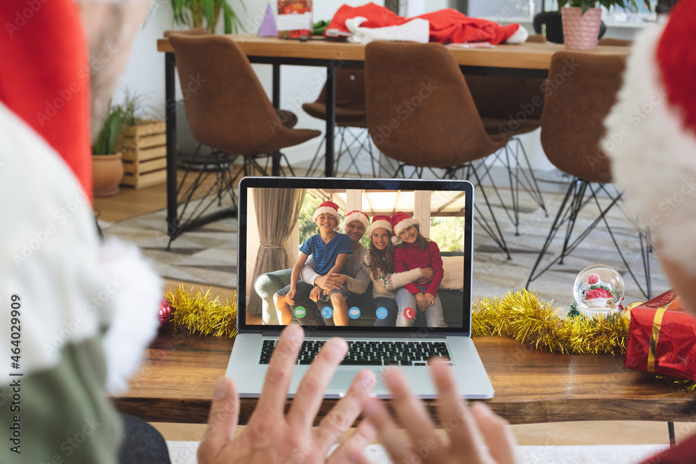 Caucasian couple in santa hat on christmas video call on laptop with family