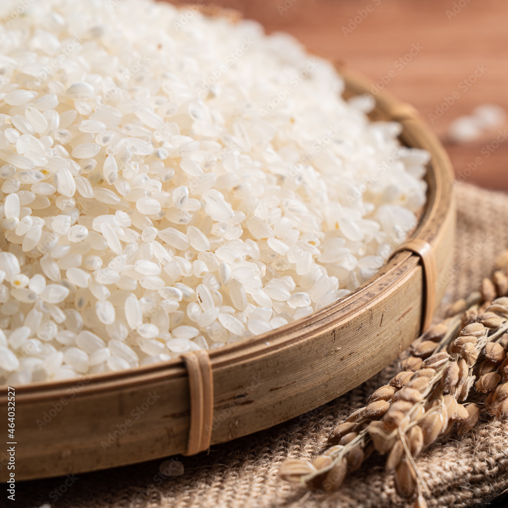 Raw white rice in a wooden bowl over table.