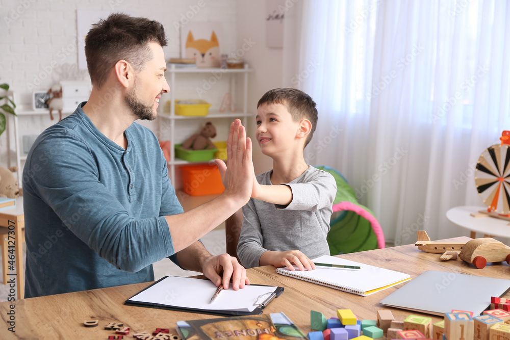 Male psychologist working with little boy in office. Autism concept