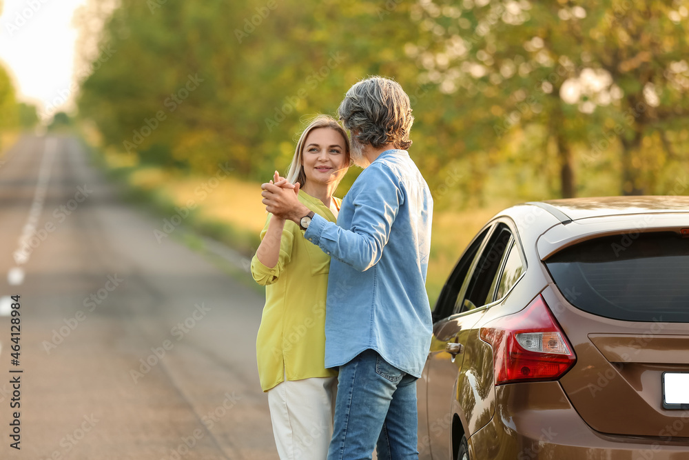 Happy mature couple dancing near car outdoors