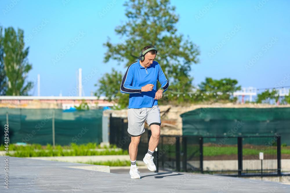 戴着耳机在户外跑步的运动型成熟男子