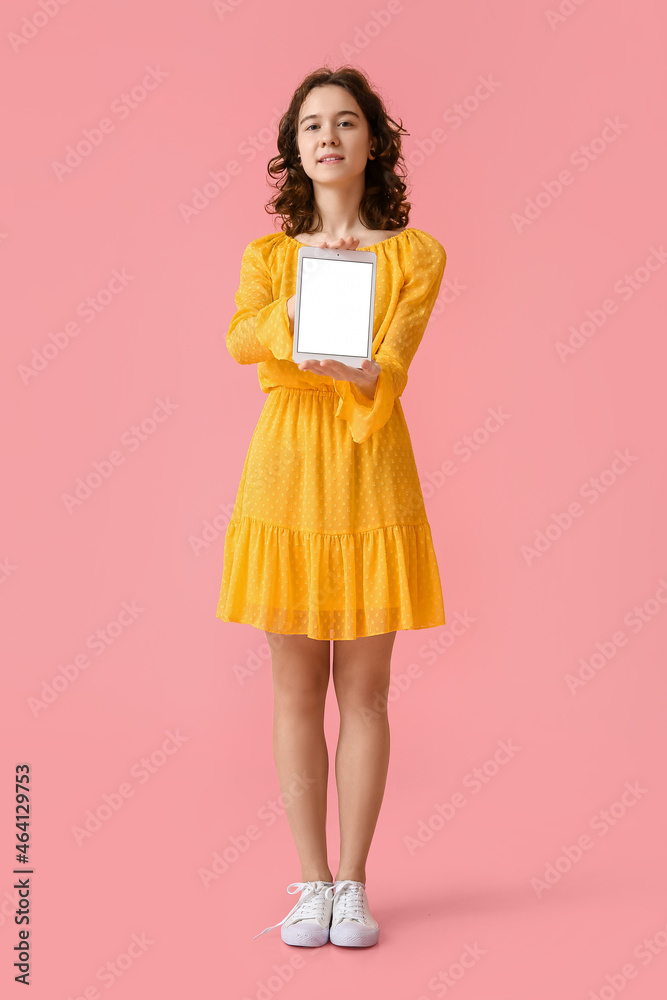 Pretty teenage girl with tablet computer on pink background