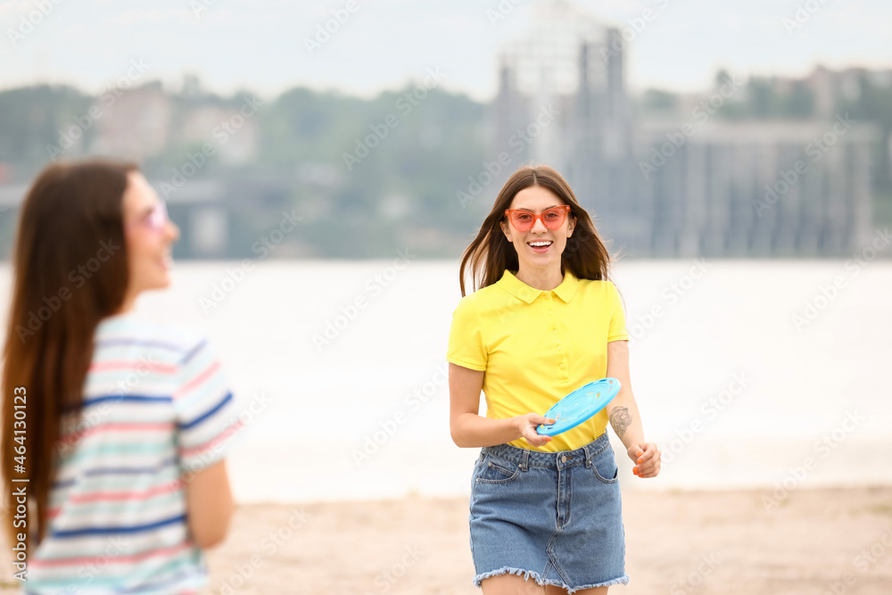 美丽的年轻女子在河边玩飞盘