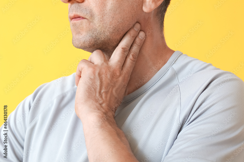 Male runner checking pulse on color background