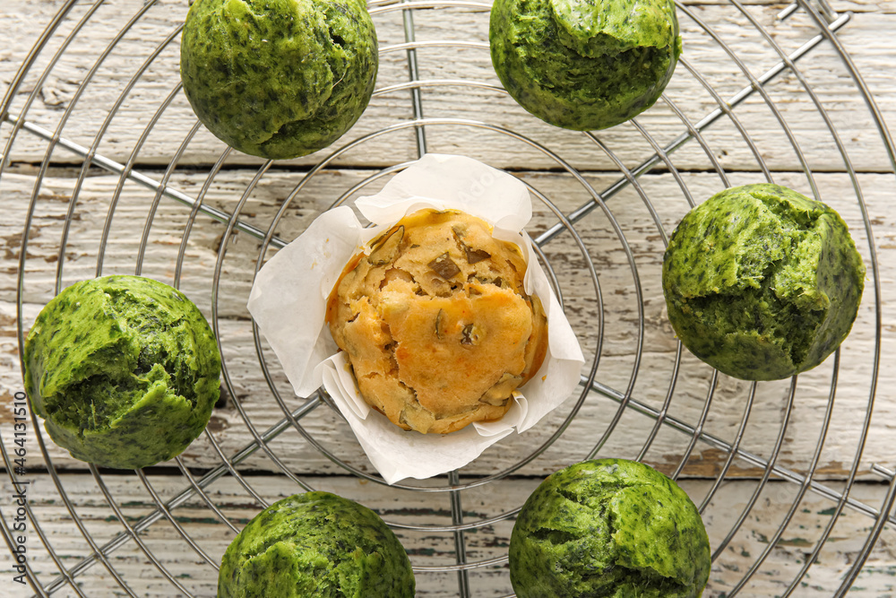 Grid with tasty spinach muffins on light wooden background