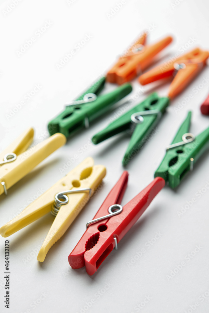 Different plastic clothespins on grey background, closeup