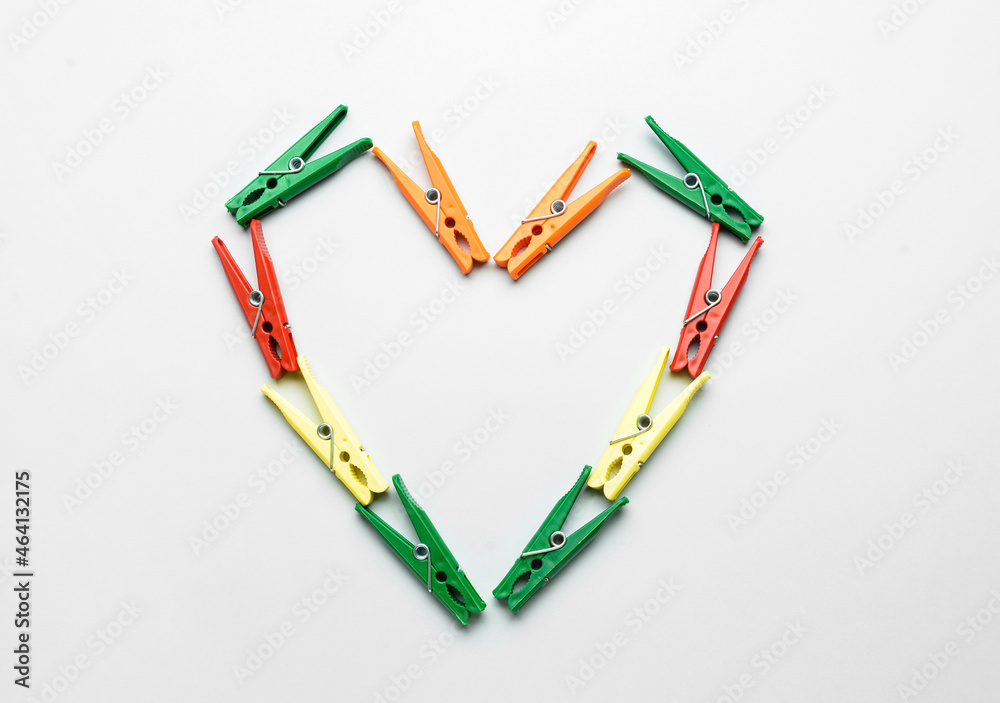 Heart made of plastic clothespins on grey background