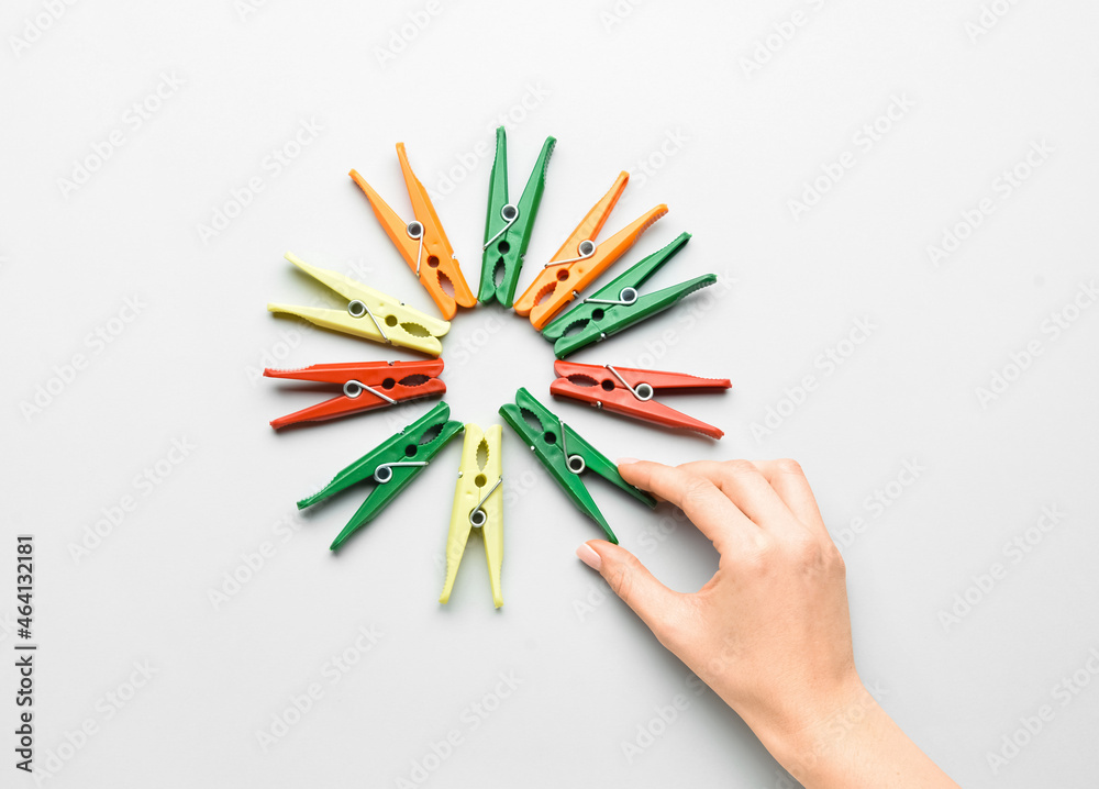 Female hand and plastic clothespins on grey background