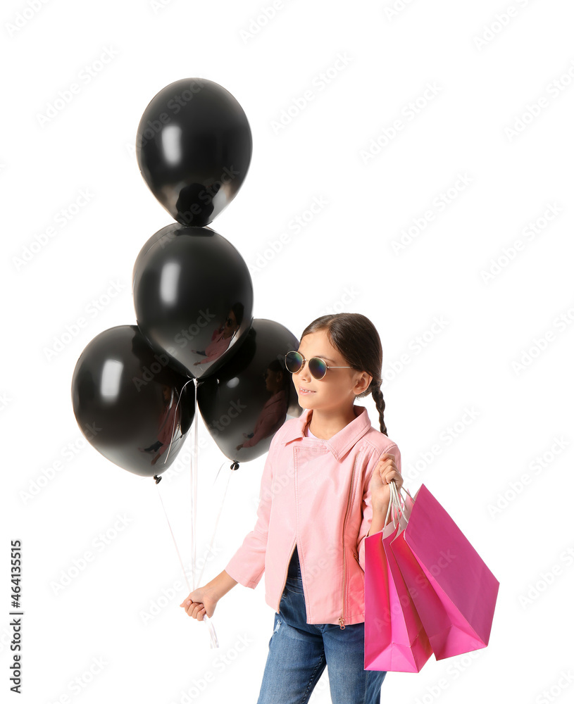 Little girl with Black Friday shopping bags and balloons on white background