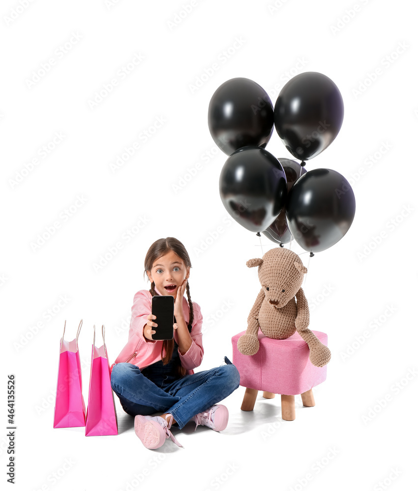 Surprised little girl with mobile phone on white background. Black Friday sale