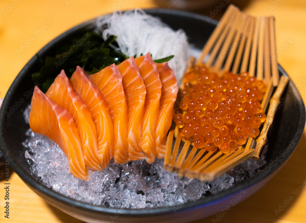 Salmon Sashimi and ikura salmon egg in Japanese buffet restaurant menu.black plate salmon slices.Asi