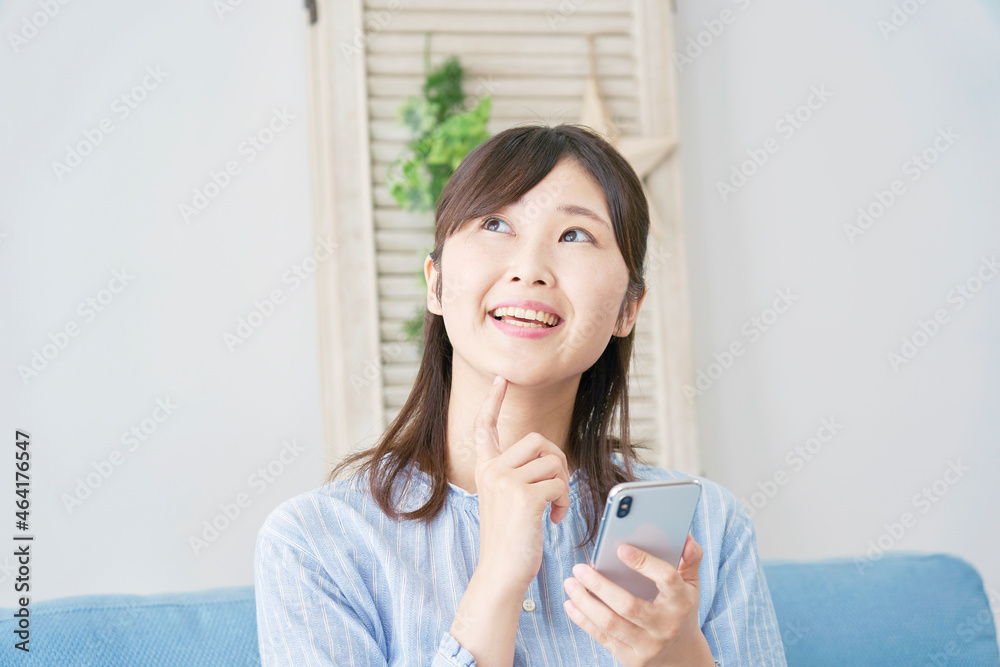 部屋でスマホを使う女性　考える