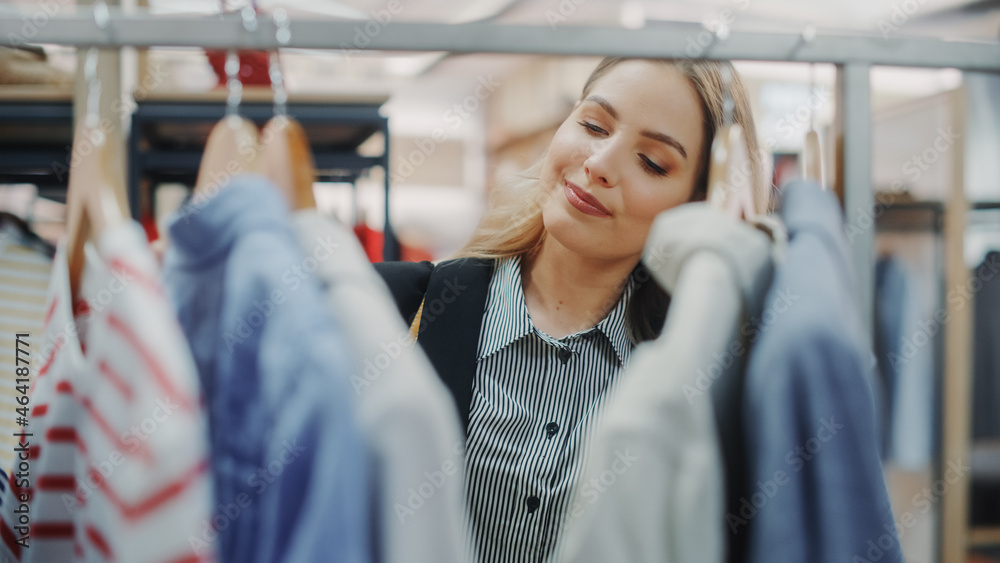 美丽微笑的女顾客在服装店购物，选择时尚的衣服，挑选金发