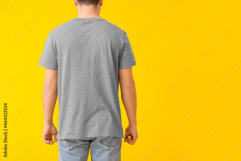 Handsome young man in stylish t-shirt on color background, back view