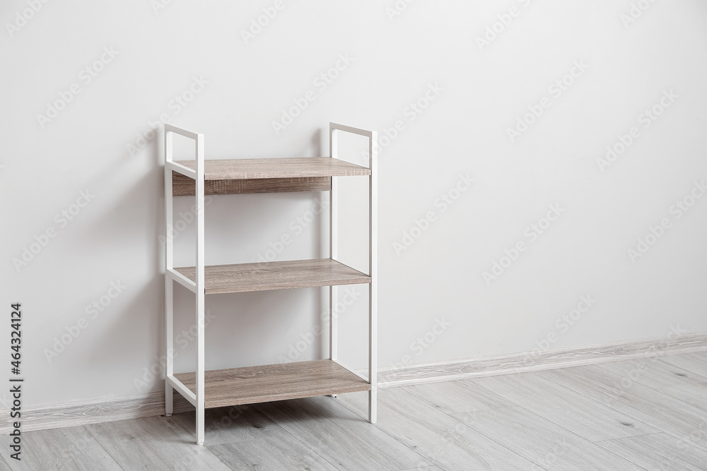 Stylish shelf unit near light wall