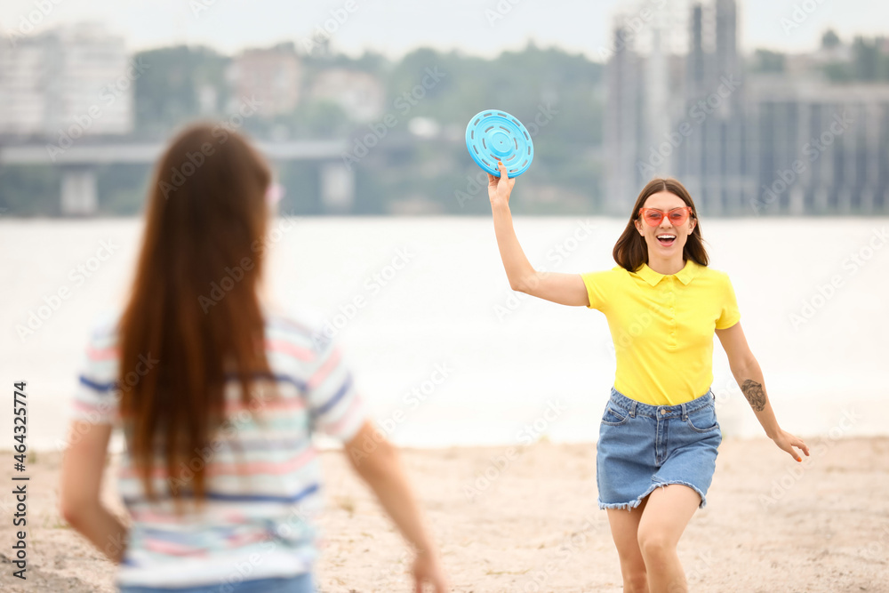 美丽的年轻女子在河边玩飞盘