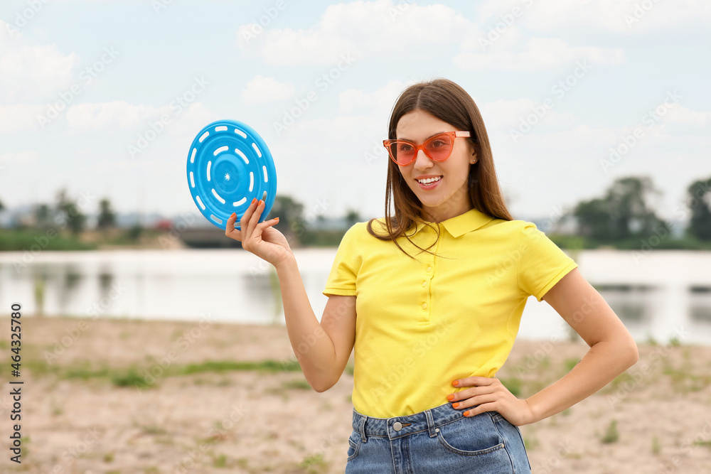 Beautiful young woman playing frisbee outdoors