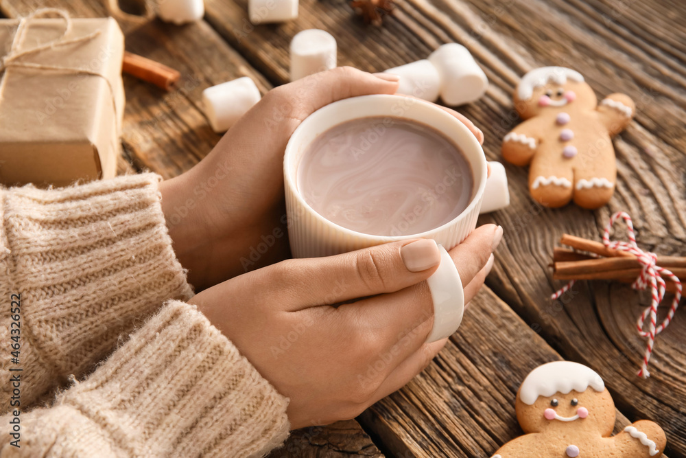 Female hands with cup of cacao on wooden table, closeup