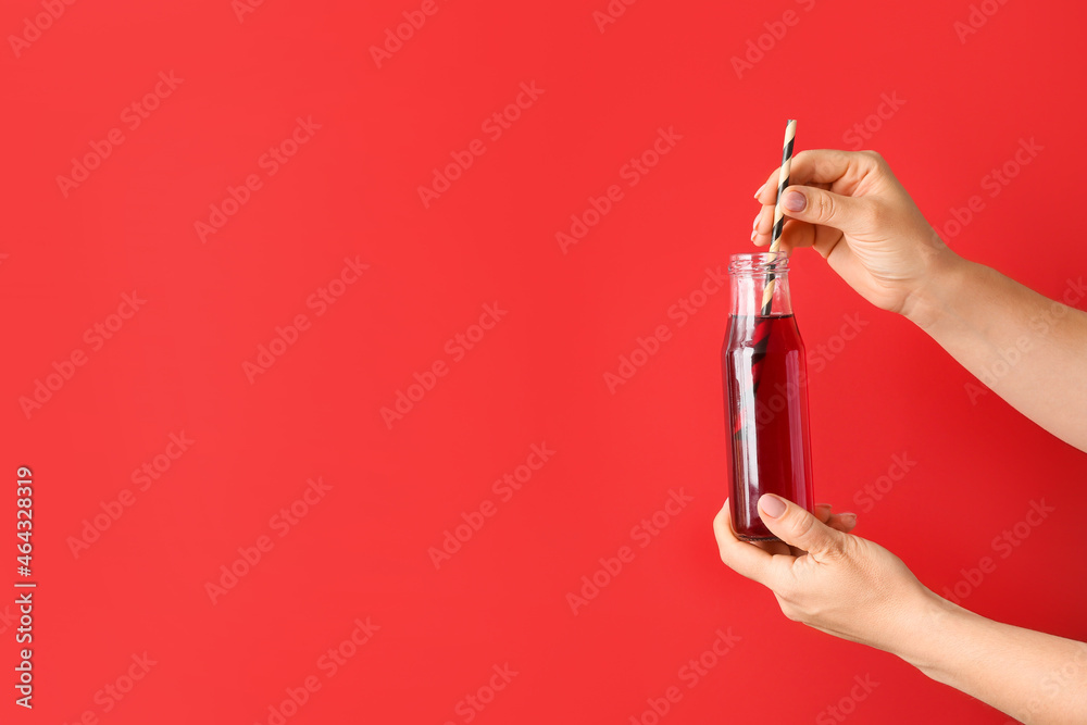 Female hands with bottle of healthy juice on color background