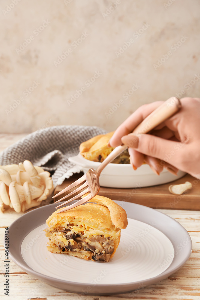 Woman eating piece of tasty mushroom pot pie at table